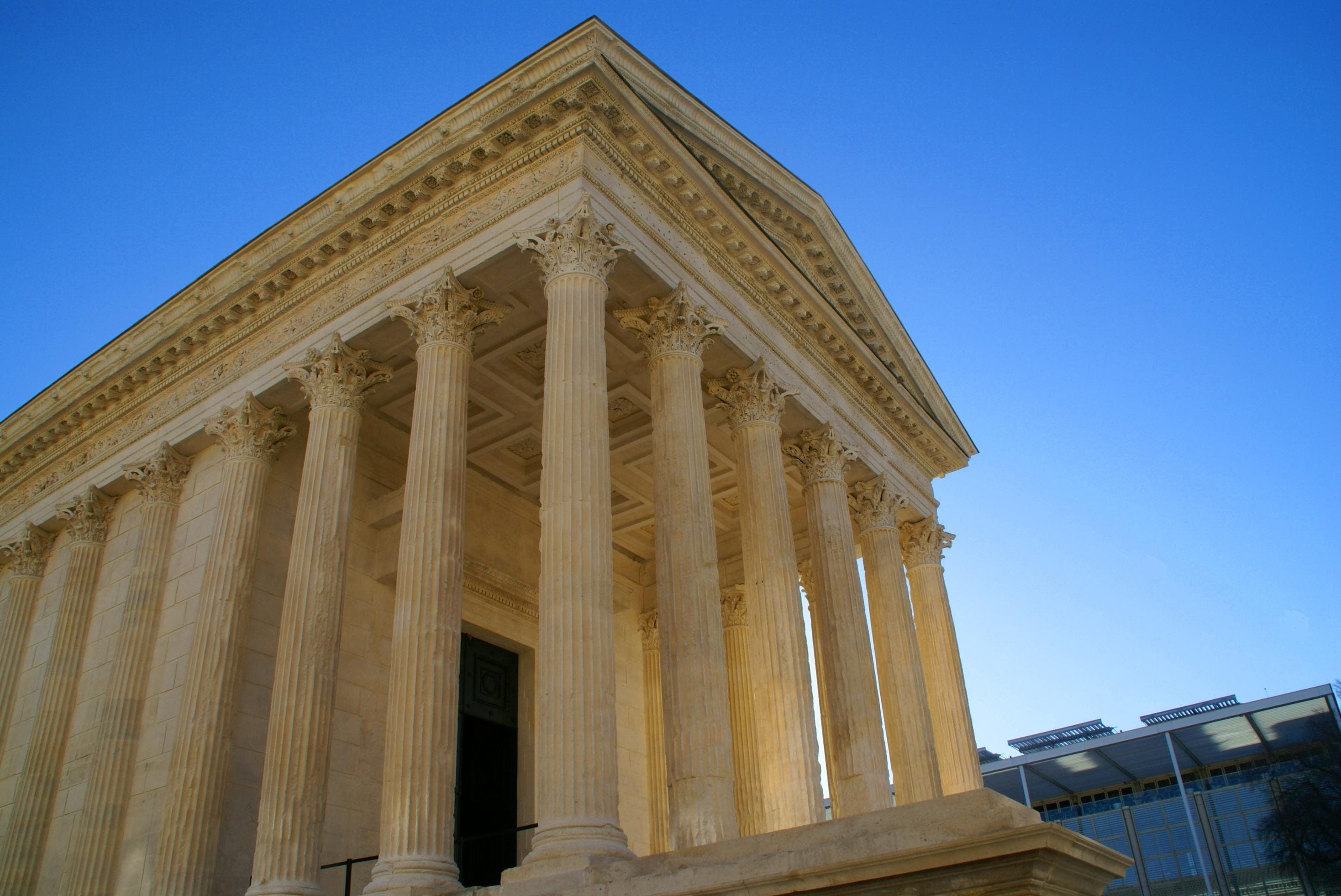 Le fronton de la Maison Carrée de Nîmes et le Carré d’Art en arrière plan se détachent sur le ciel bleu