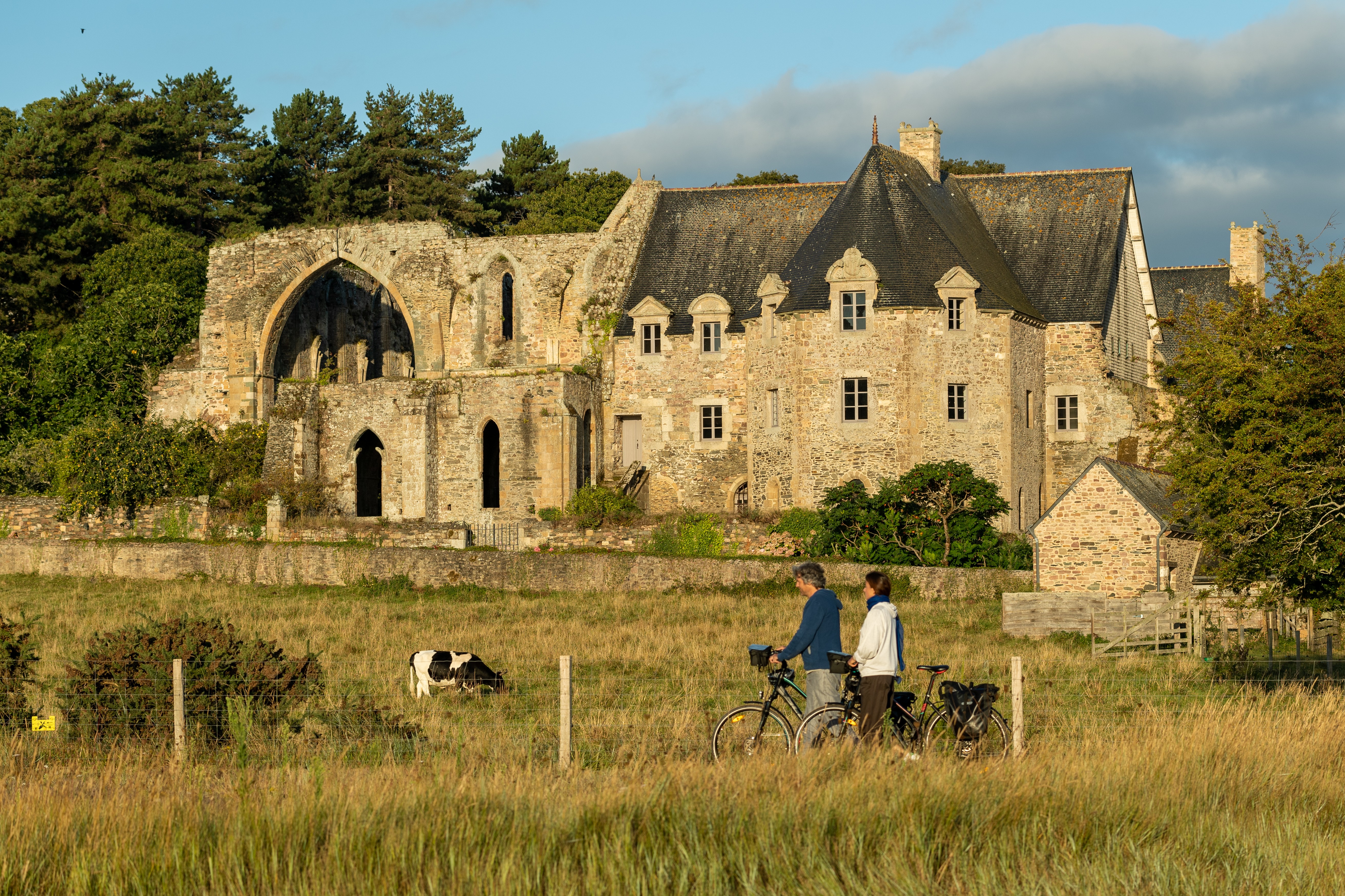 Abbaye de Beauport à Paimpol, vue de l’Abbaye et du sentier des douaniers qui la longe côte du Goëlo avec deux cyclistes marchand à côté de leur vélo