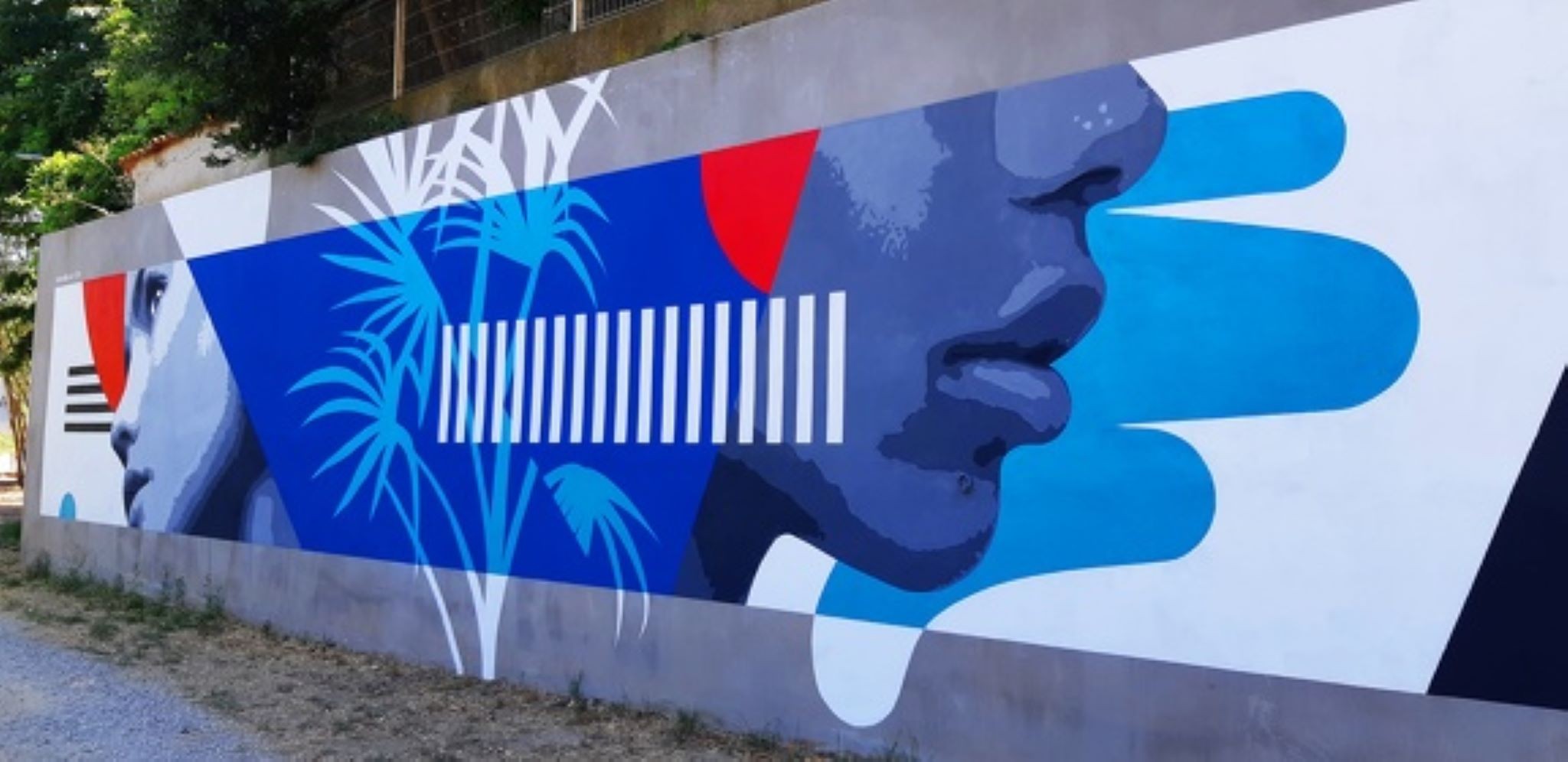 Fresque murale colorée représentant des profils de visages humains stylisés et des motifs géométriques 