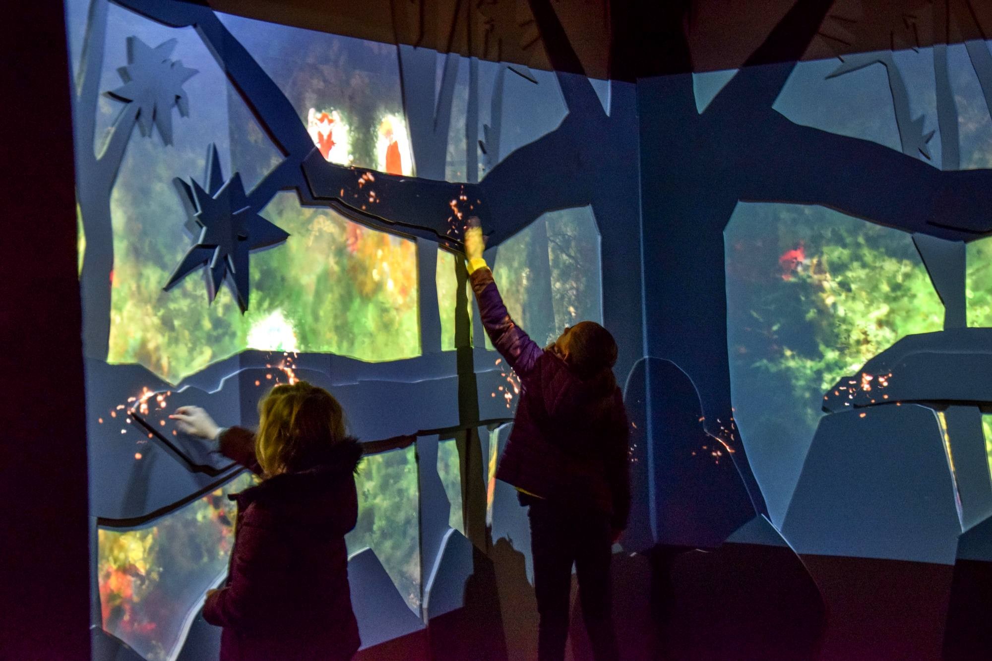 Enfants interagissant avec des projections dans le couloir des Korrigans à la Porte des Secrets en Brocéliande