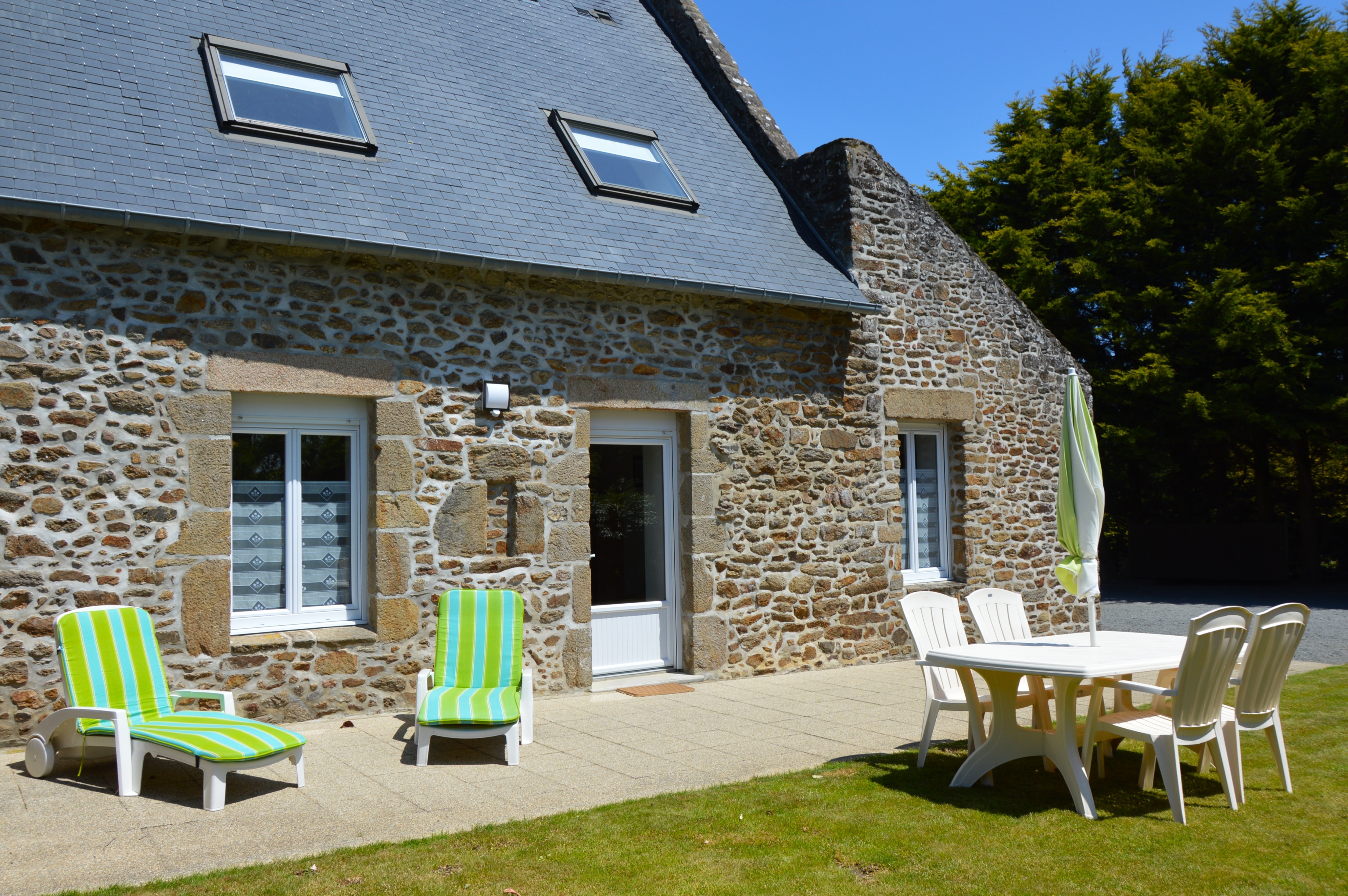 Façade en pierre du Gîte 2 avec terrasse, jardin, balançoire, bac à sable et stationnements privatifs. Accès indépendant.