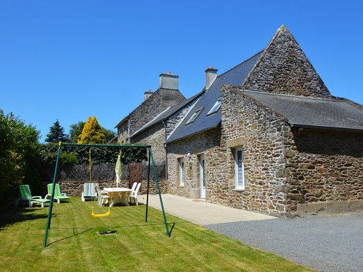 Façade en pierre du Gîte 2 avec terrasse, jardin, balançoire, bac à sable et stationnements privatifs. Accès indépendant.