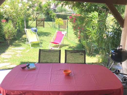 La terrasse couverte côté jardin avec table et chaises pour les repas et la détente en extérieur.