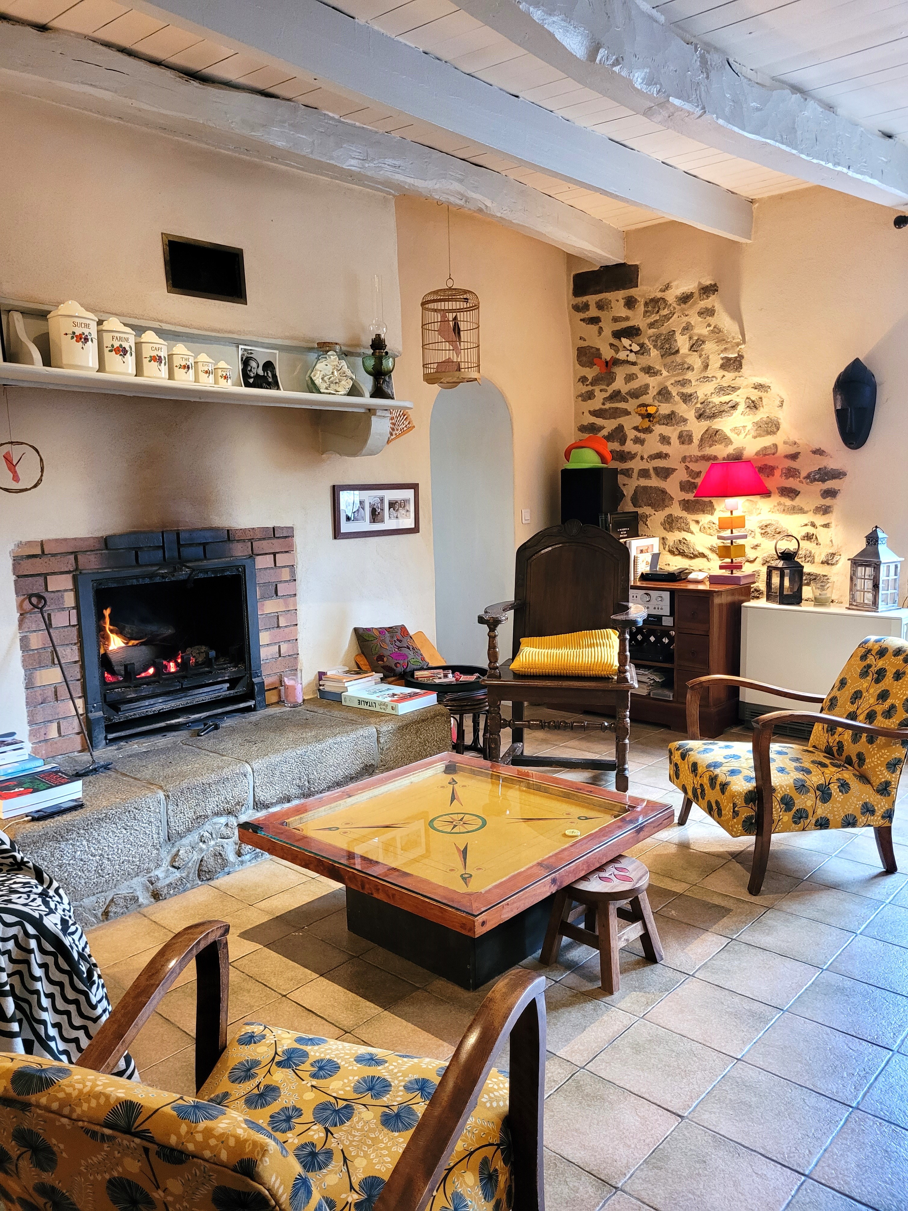 La pièce de vie avec un coin salon et son agréable cheminée, un coin séjour, l'escalier donnant accès à la mezzanine et à votre chambre. Au fond à gauche la cuisine. au fond à droite une pièce espace détente avec bibliothèque, canapé et TV, rameur, table