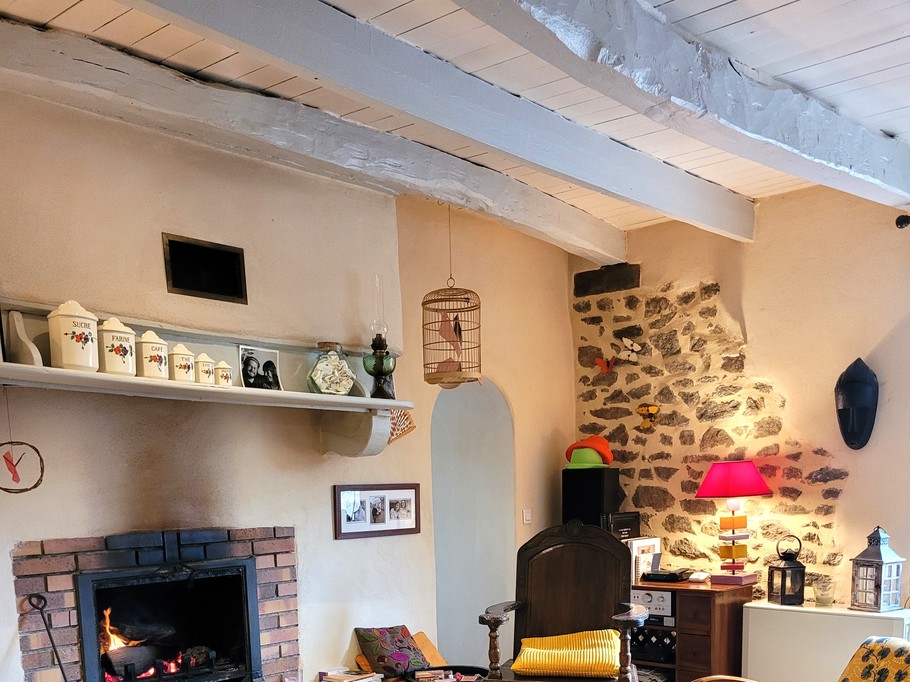 La pièce de vie avec un coin salon et son agréable cheminée, un coin séjour, l'escalier donnant accès à la mezzanine et à votre chambre. Au fond à gauche la cuisine. au fond à droite une pièce espace détente avec bibliothèque, canapé et TV, rameur, table