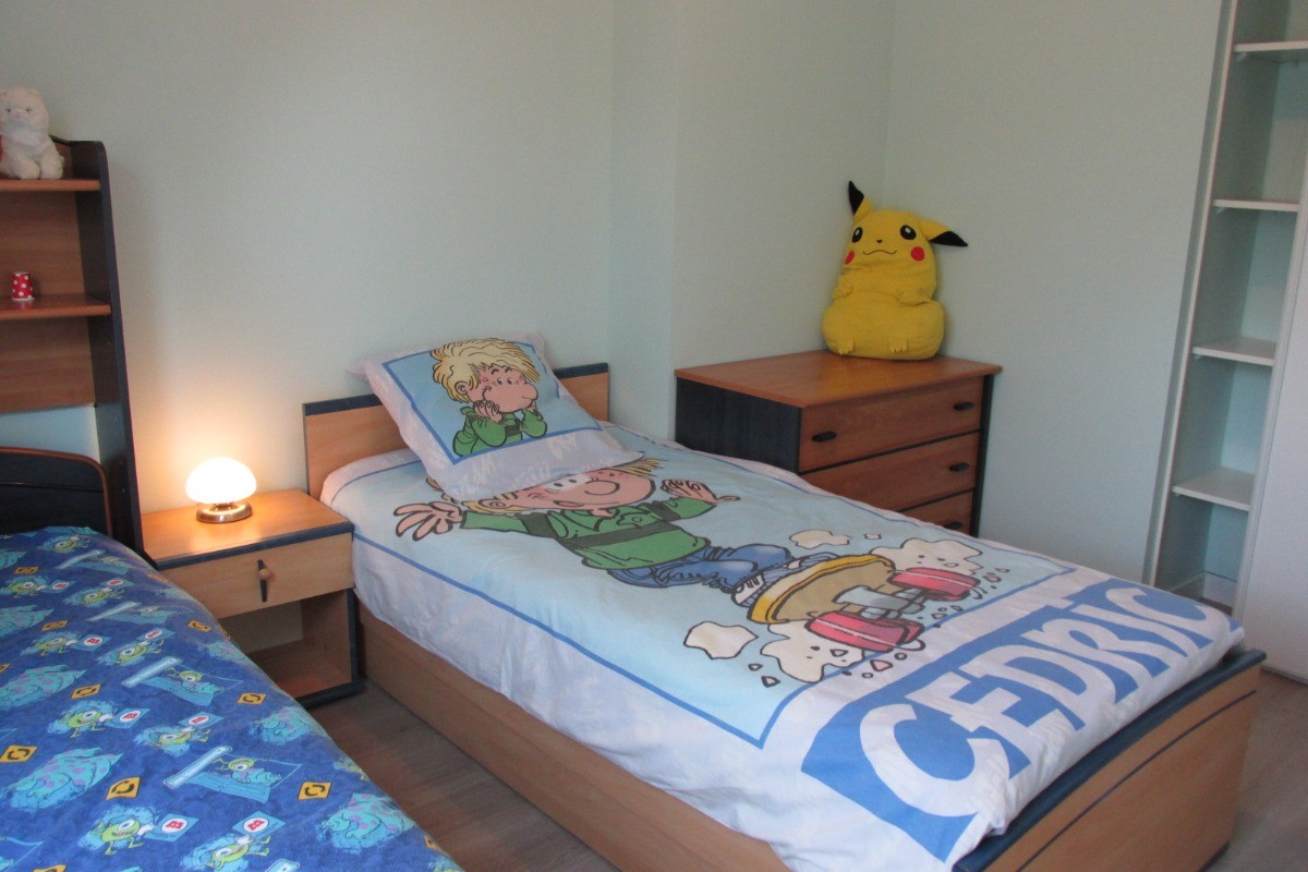 Chambre enfants avec une commode et placard-rangement.