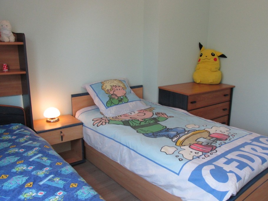 Chambre enfants avec une commode et placard-rangement.