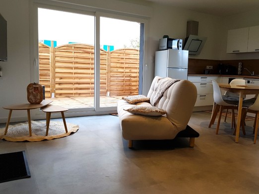 Pièce de vie au rez-de-chaussée avec coin salon avec TV, et coin cuisine et sa table à manger. Canapé convertible pour 2 personnes. Terrasse en bois accessible par un portillon ou par la baie vitrée.