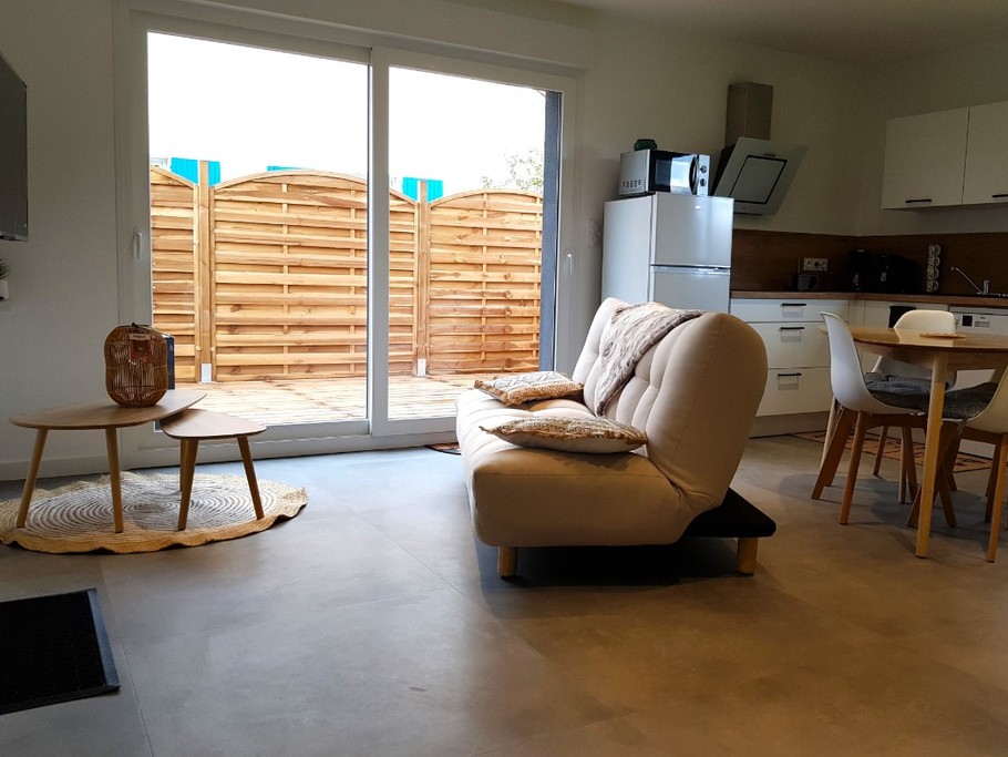 Pièce de vie au rez-de-chaussée avec coin salon avec TV, et coin cuisine et sa table à manger. Canapé convertible pour 2 personnes. Terrasse en bois accessible par un portillon ou par la baie vitrée.
