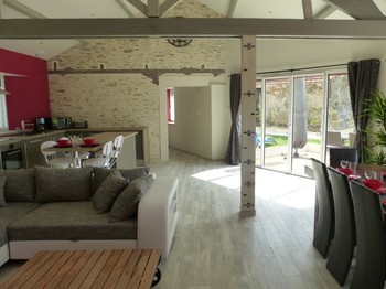 Pièce de vie avec canapé-lit, table de salle à manger, ilot central et cuisine entièrement équipée.