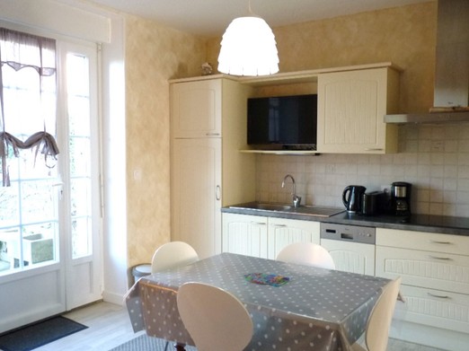 Coin séjour et cuisine toute équipée dans la pièce de vie, avec accès direct à la terrasse privative.