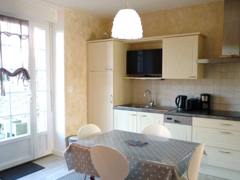 Coin séjour et cuisine toute équipée dans la pièce de vie, avec accès direct à la terrasse privative.