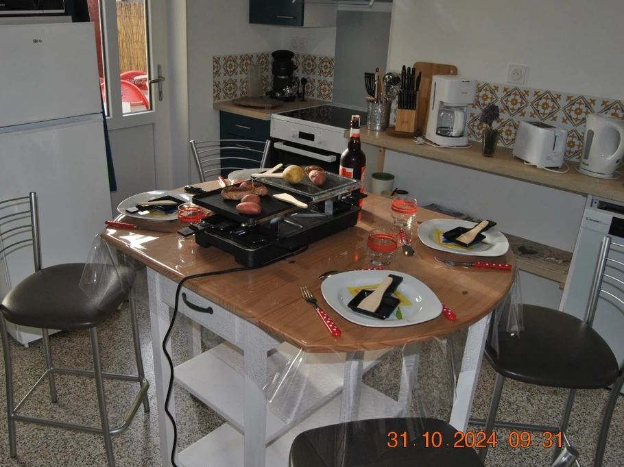 Un appareil de convivialité 3 en 1 (raclette, grill, pierrade) pour un petit repas d'automne sur une table haute et les 4 chaises.