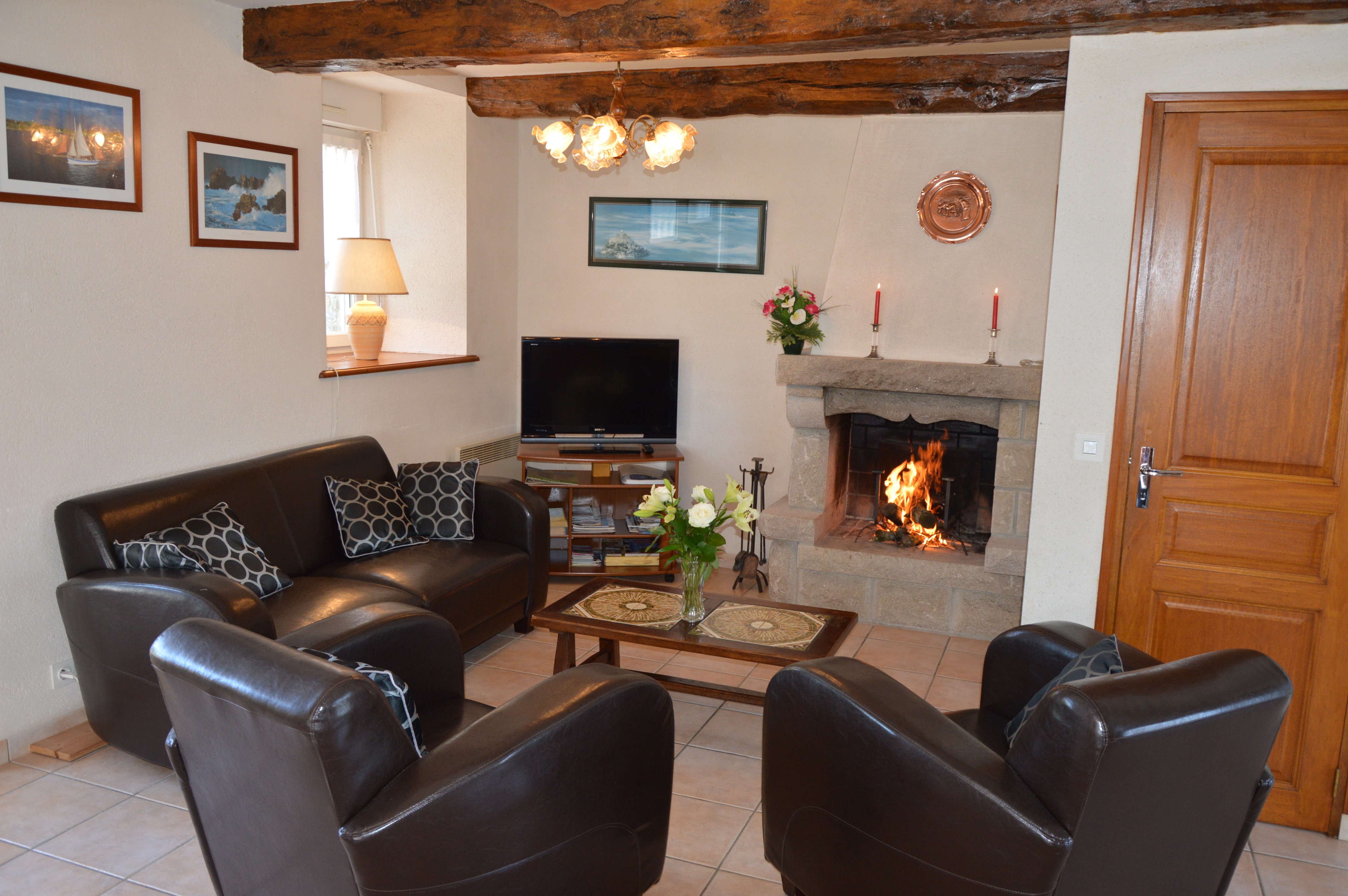 Pièce de vie agréable avec poutres apparente. Coin salon avec de confortables canapés et fauteuils en cuir. Cheminée décorative.