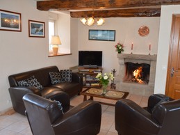 Pièce de vie agréable avec poutres apparente. Coin salon avec de confortables canapés et fauteuils en cuir. Cheminée décorative.