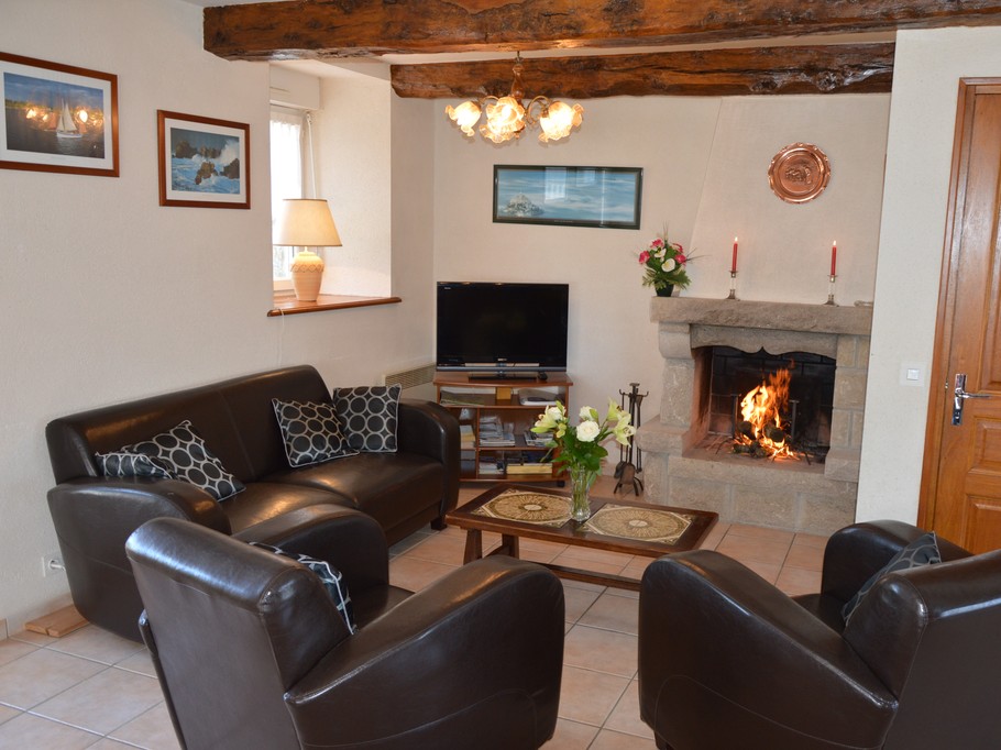 Pièce de vie agréable avec poutres apparente. Coin salon avec de confortables canapés et fauteuils en cuir. Cheminée décorative.