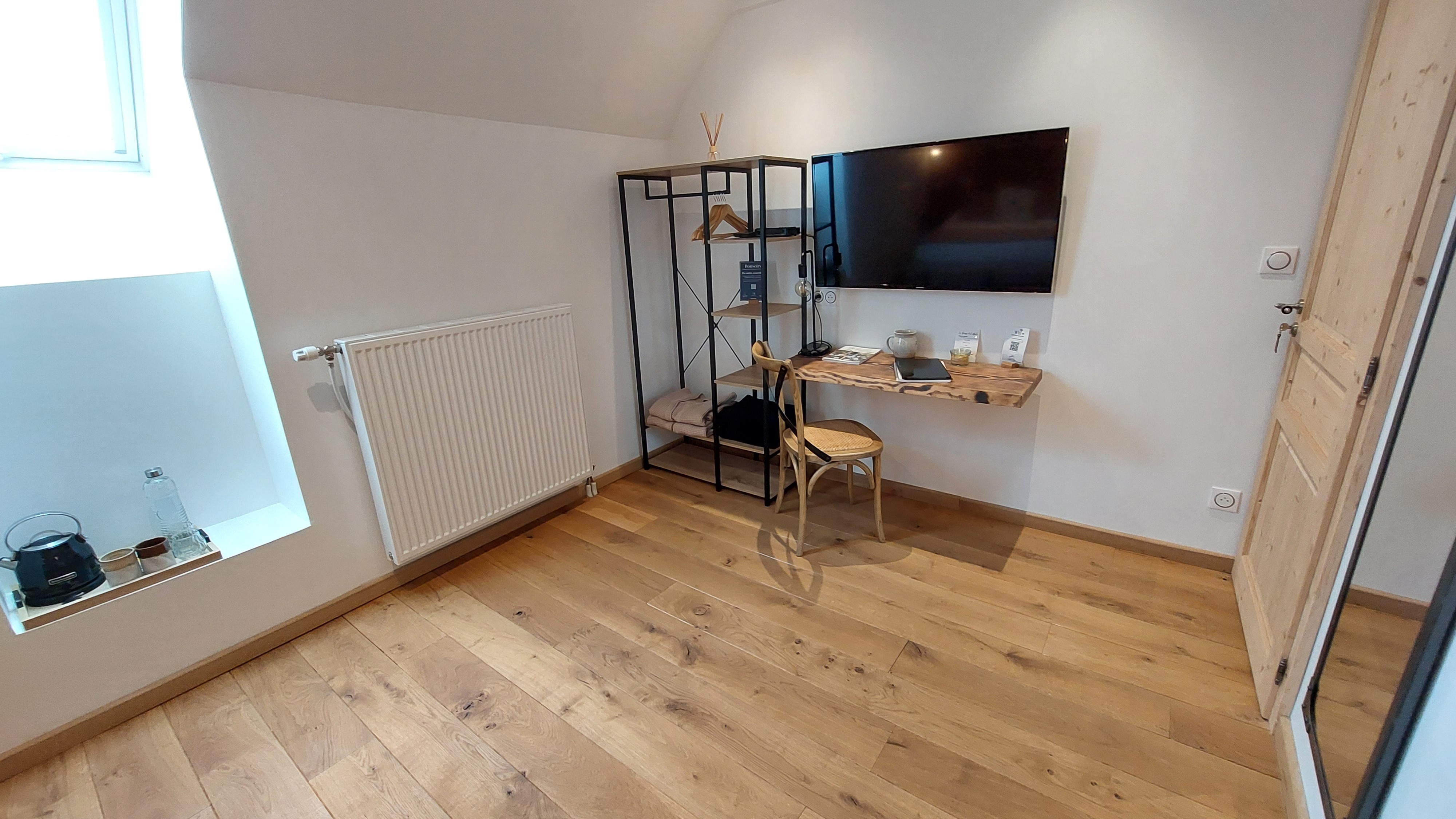 Office space and television in a renovated guest room in the Cantal region