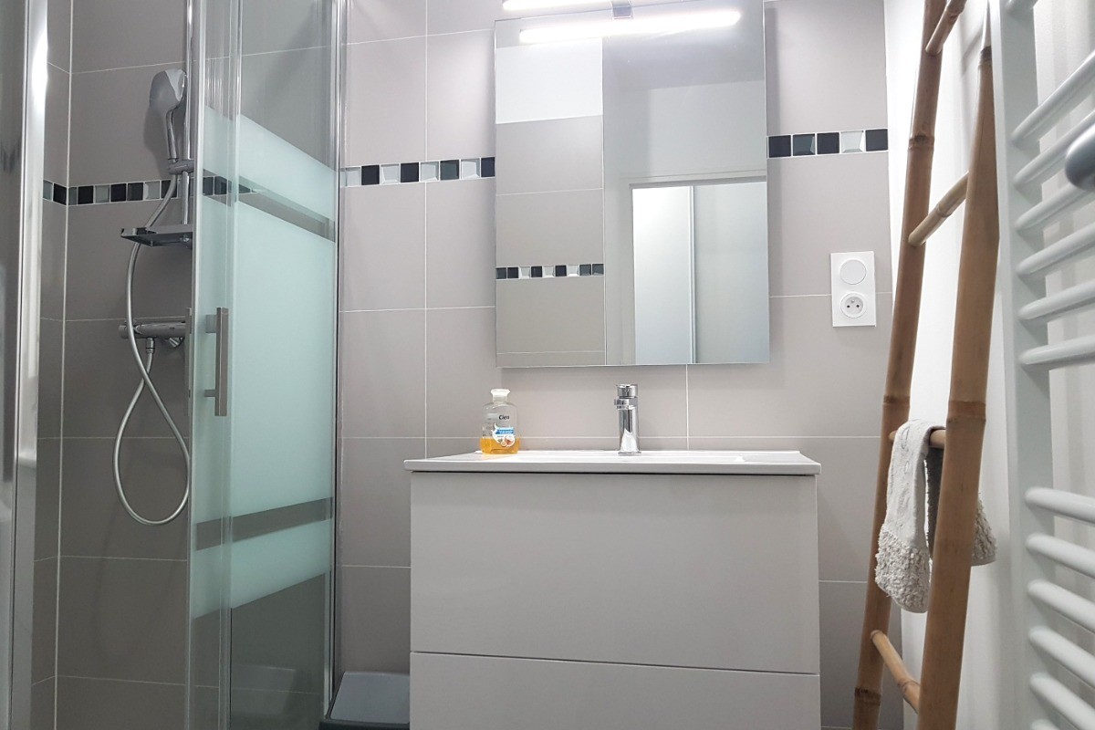 Salle d'eau avec une douche grande dimension, lavabo meuble vasque, machine à laver, sèche serviette électrique. WC séparé.