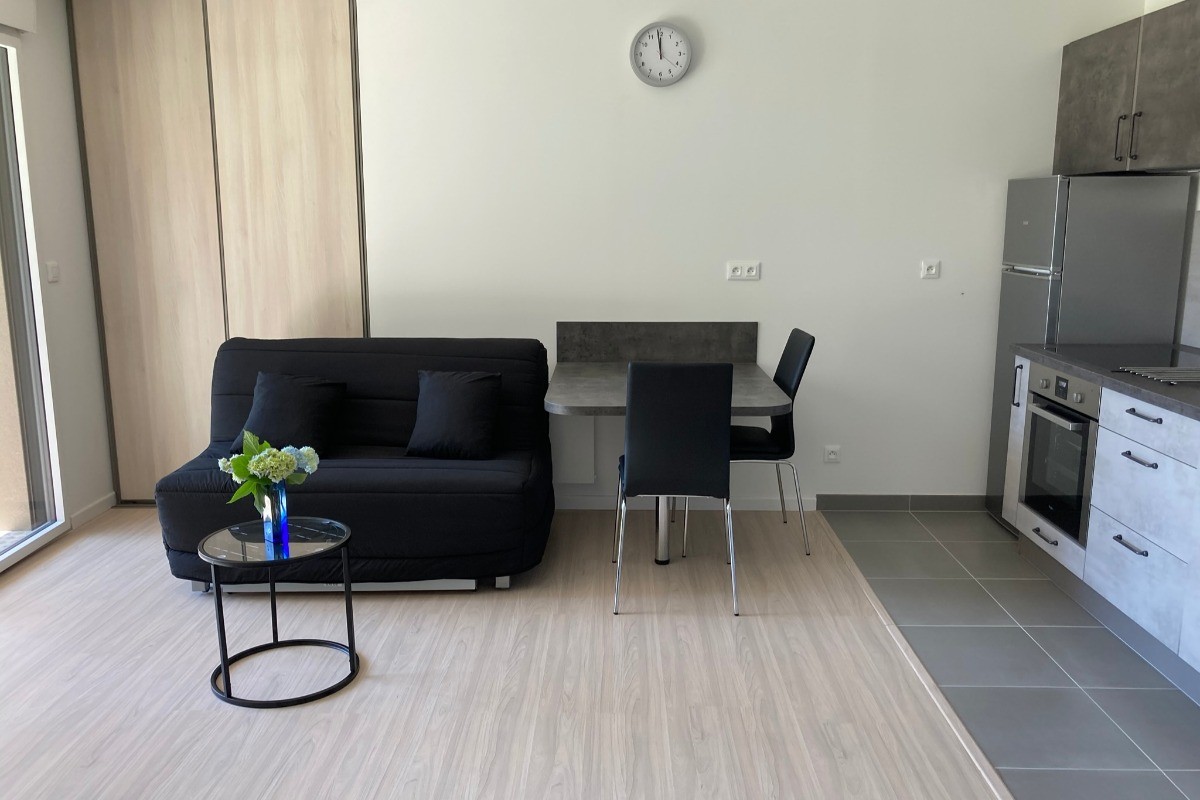 Coin repas avec cuisine aménagée et banquette de canapé.