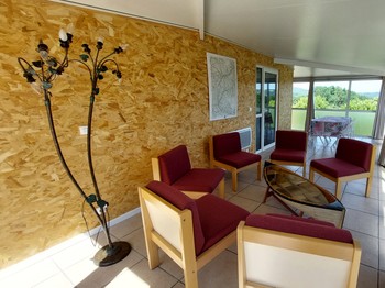 Salon dans la véranda du gîte Lilas avec vue sur le Cantal