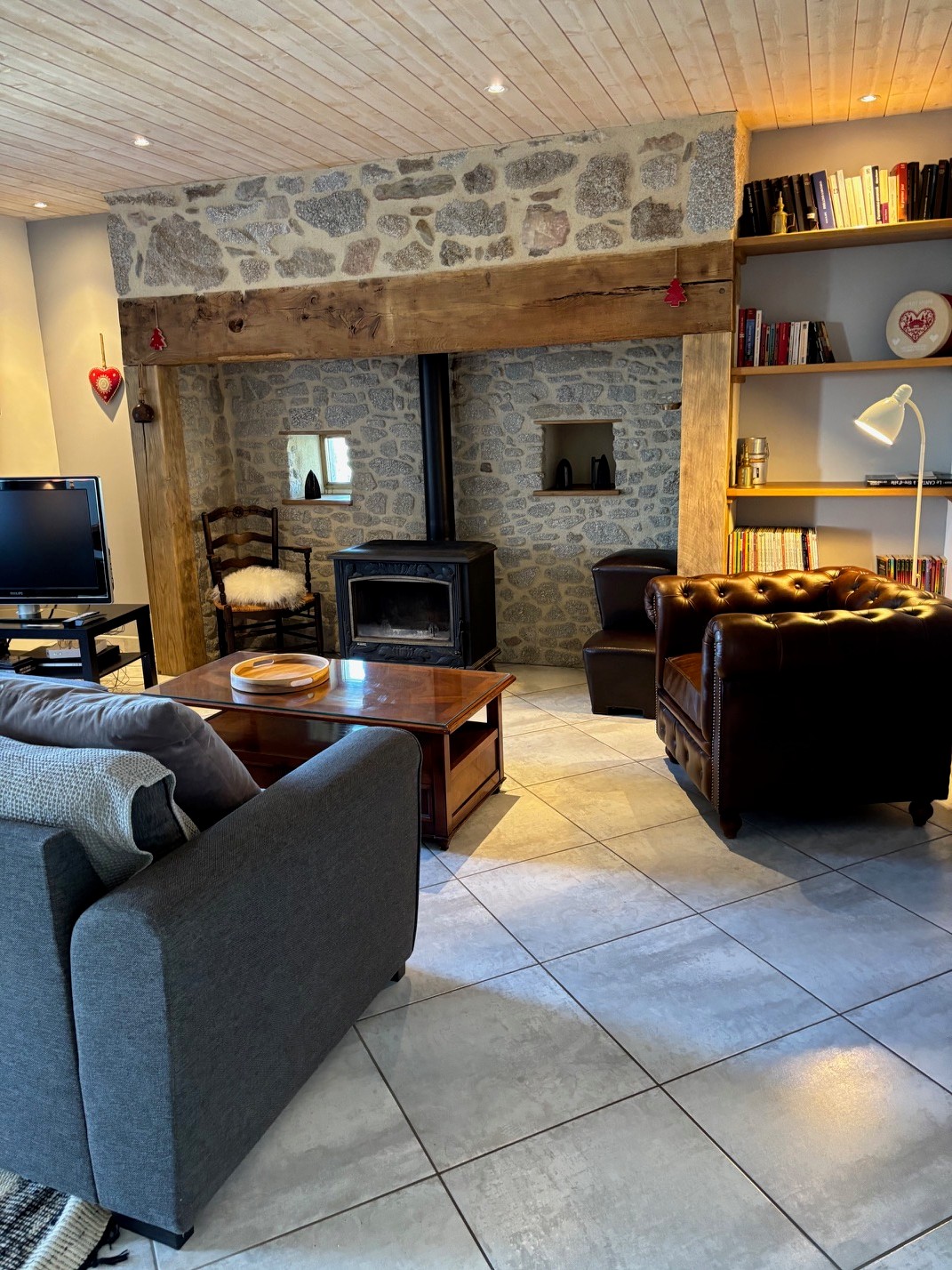 living room with inglenook fireplace and wood-burning stove warm atmosphere Cantal gîte