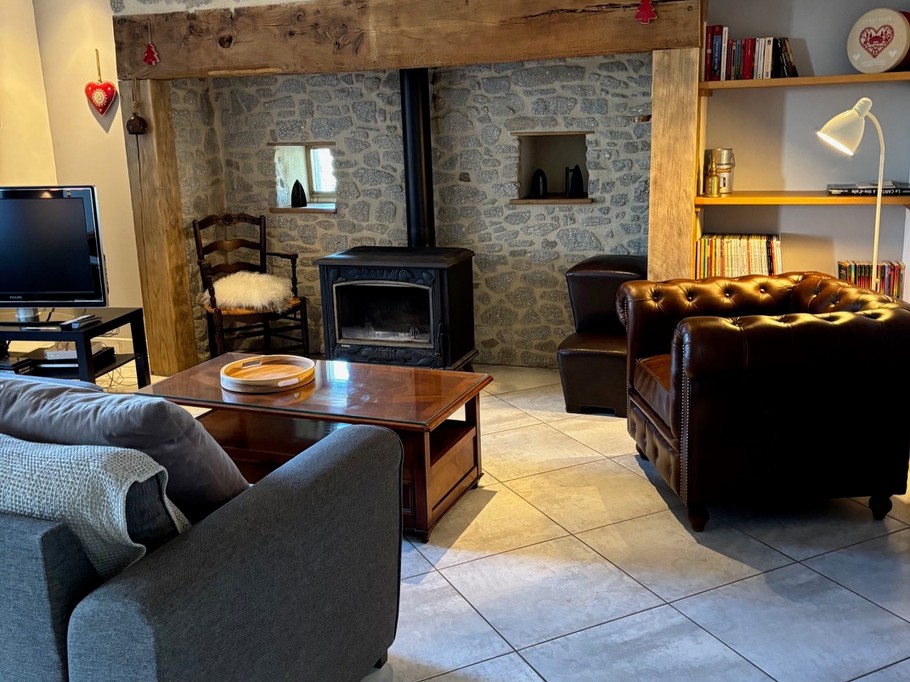 living room with inglenook fireplace and wood-burning stove warm atmosphere Cantal gîte
