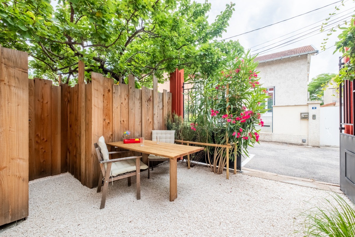 Patio à l'entrée aménagé avec table et chaise en accès libre et partagé avec les deux autres logements.