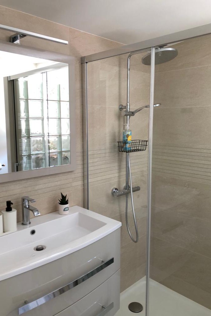 Salle d'eau moderne avec une douche grande dimension, meuble vasque et WC.