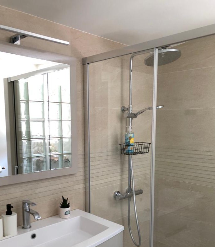 Salle d'eau moderne avec une douche grande dimension, meuble vasque et WC.