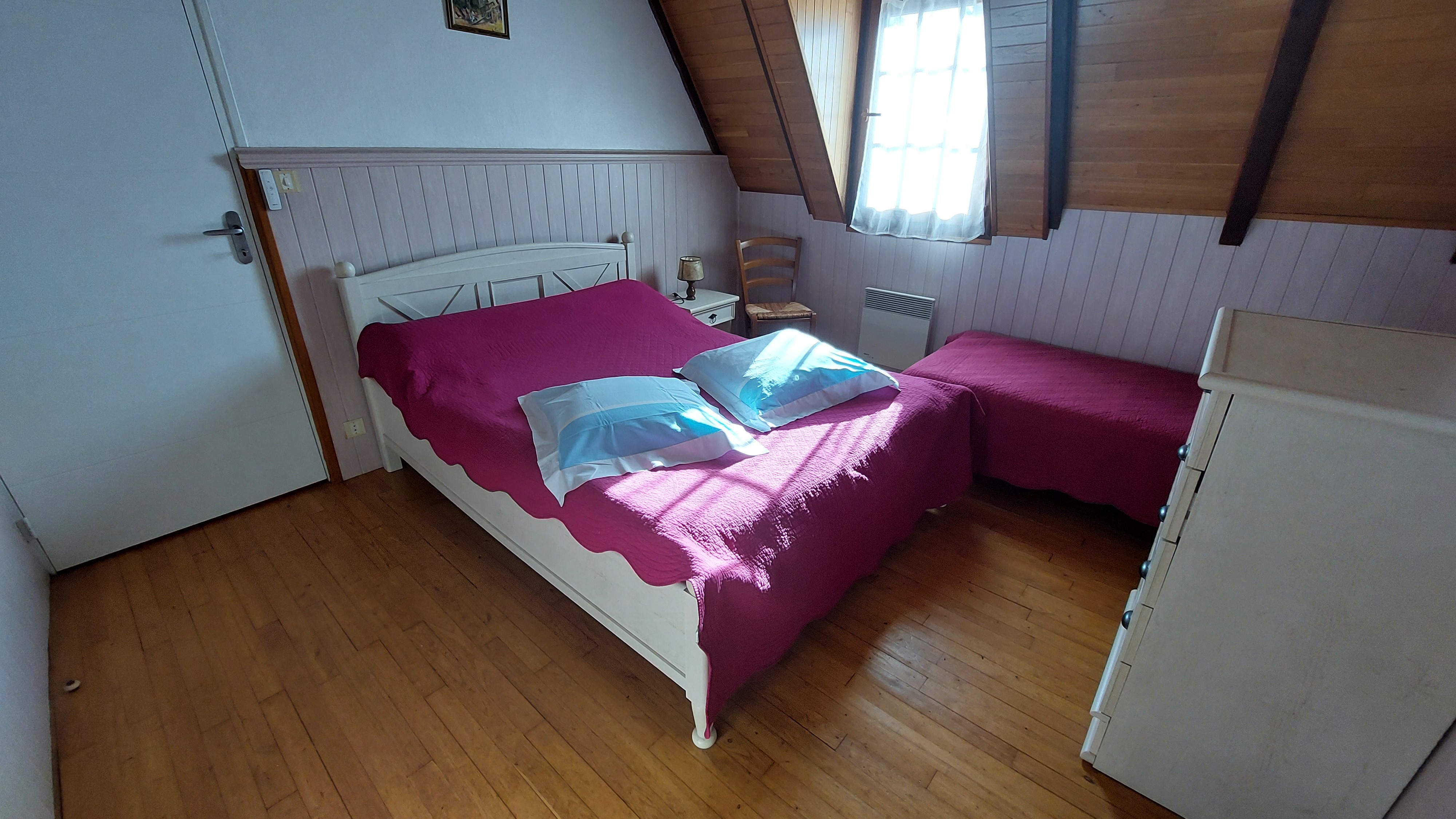 Chambre lumineuse avec lit double et vue dégagée sur la campagne environnante.