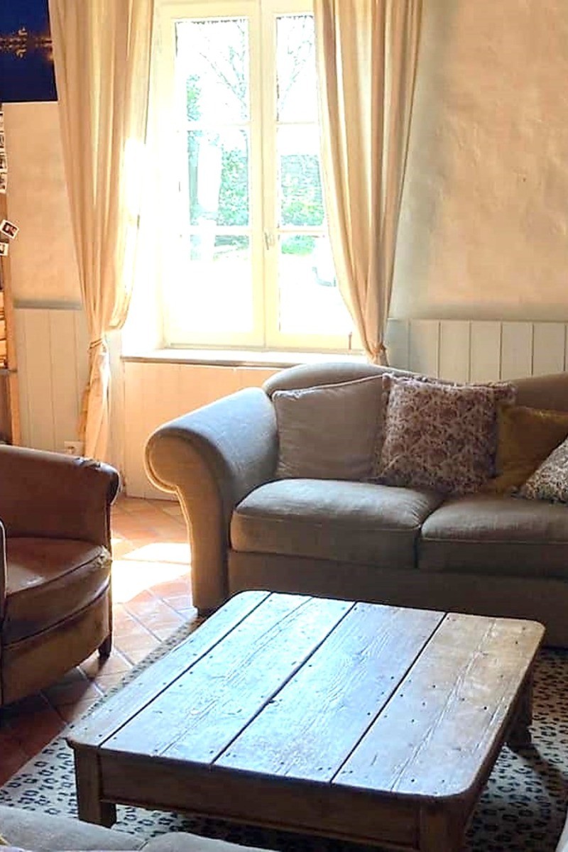 Grand salon chaleureux avec poutres apparentes et cheminée d'apparat. 
Crédits photo :  Mégane ARNAL