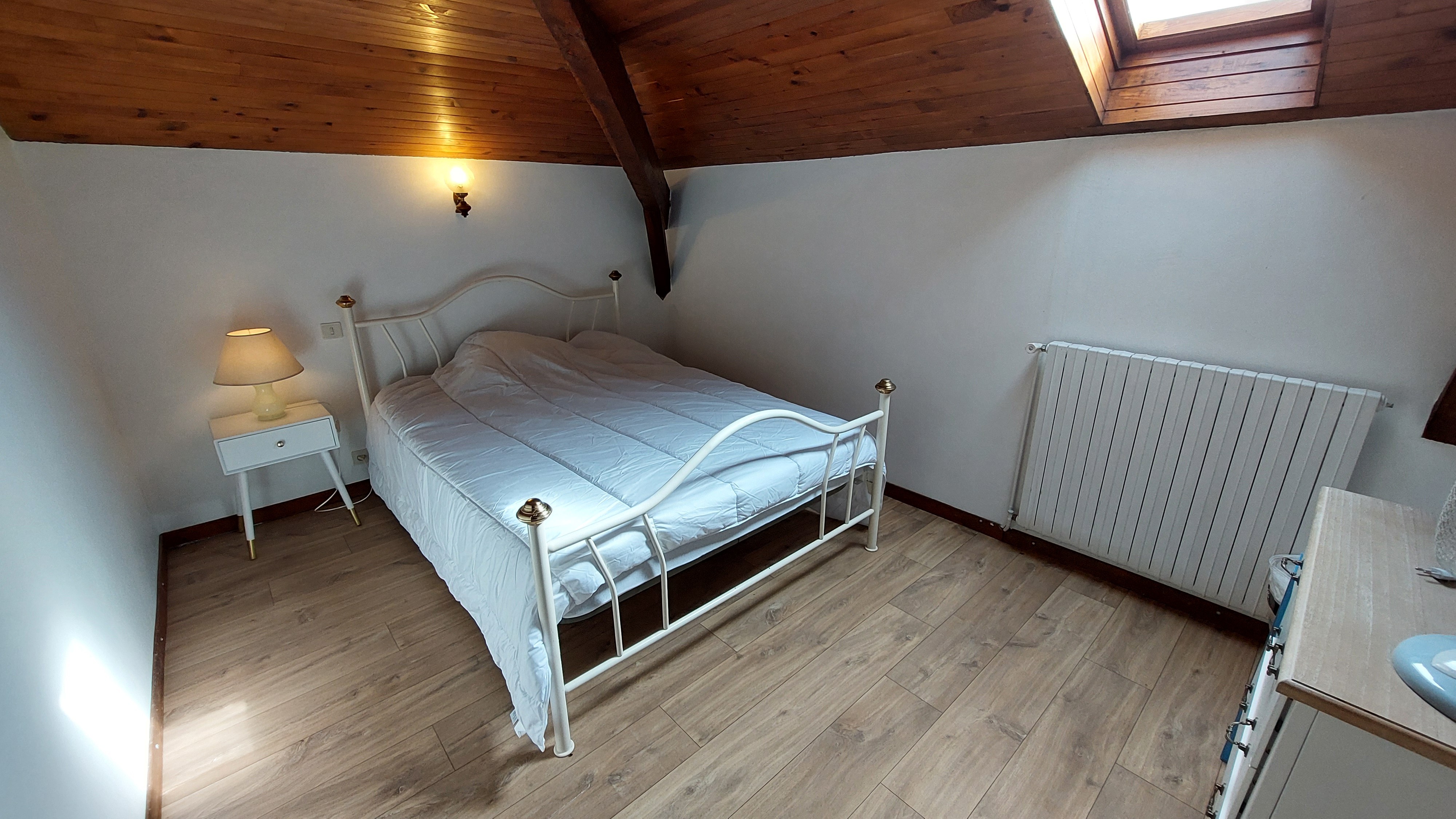 Bedroom with double bed and exposed beams in Cantal gîte