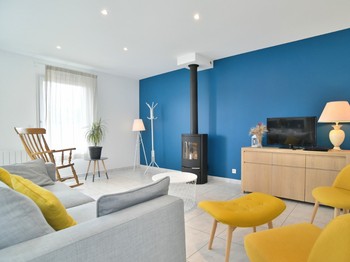 Grande pièce de vie avec coin cuisine, coin séjour et coin salon avec poêle à bois.