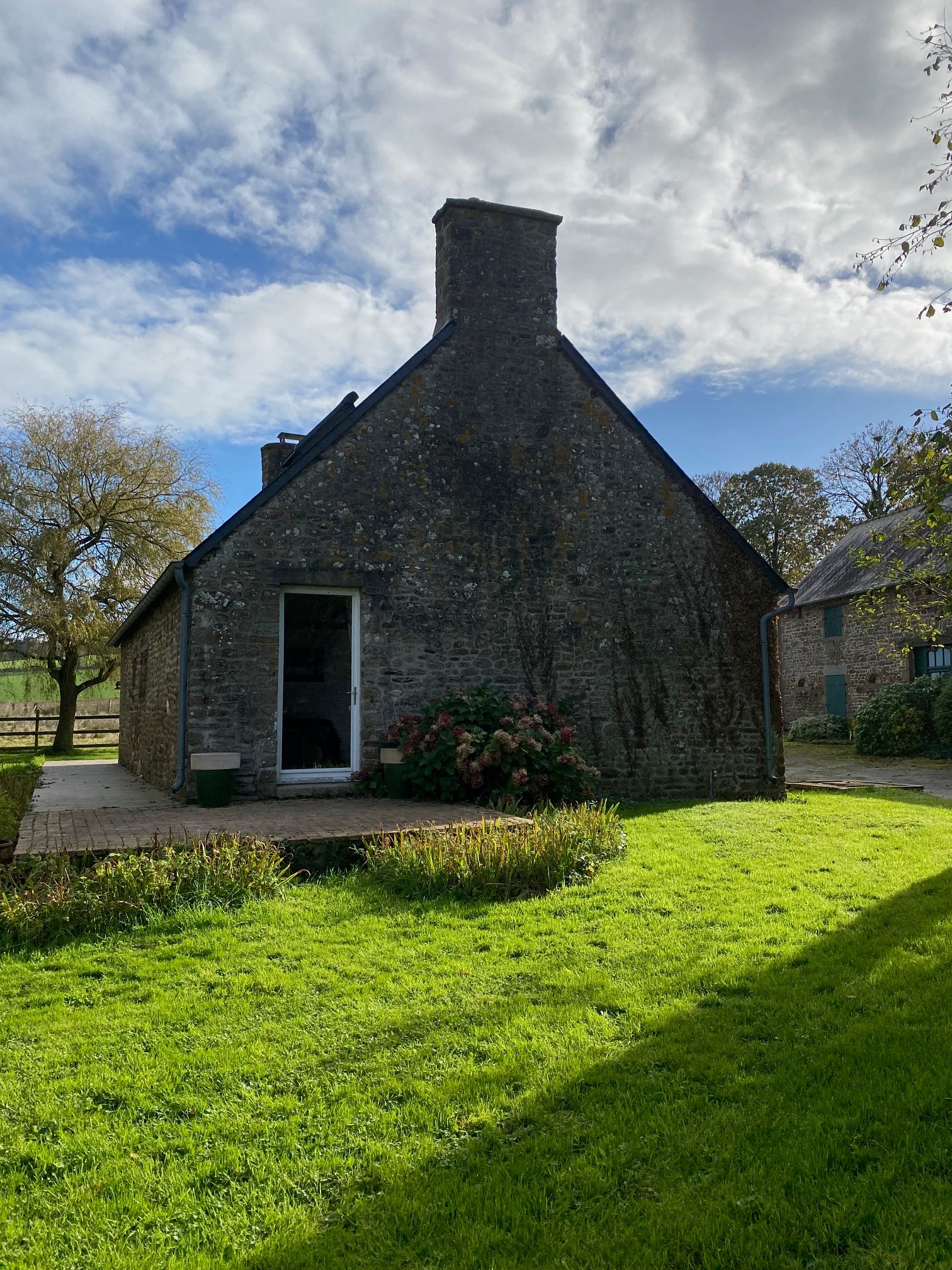 Terrasse avec salon de jardin en bois à la belle saison, barbecue, transat et pelouse. Le tout au calme en pleine campagne !