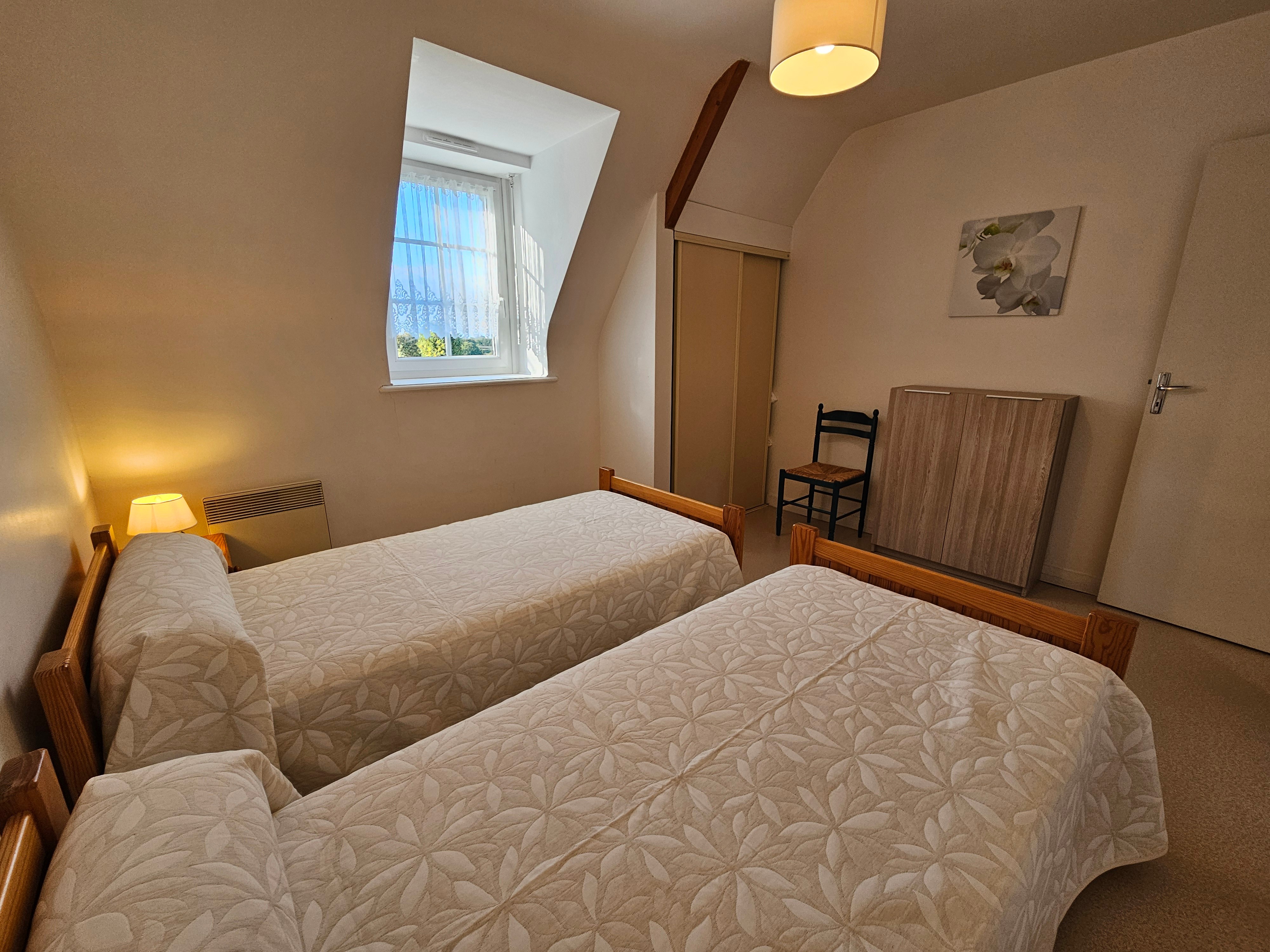 Chambre indépendante pour 2 personnes avec 2 lits 90x190 cm, commode, armoire et chaise.