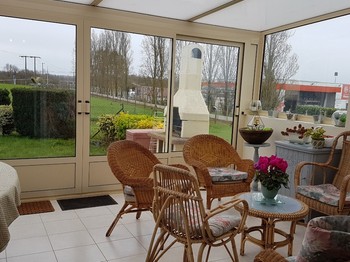 Le salon de la véranda avec accès au jardin et à la terrasse