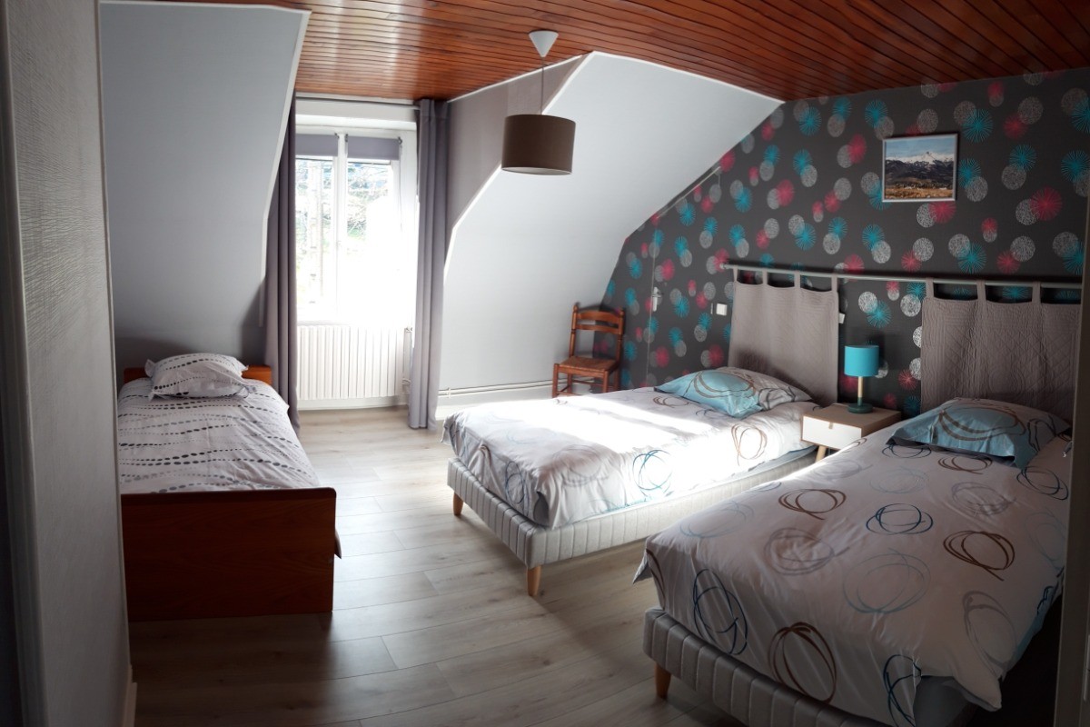 Chambre spacieuse avec trois lits simples, idéale pour les enfants ou amis.