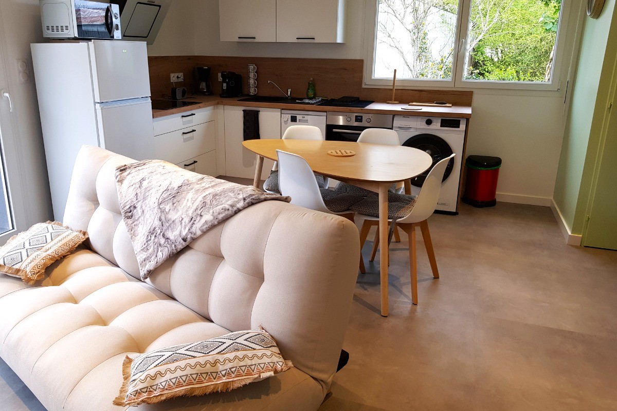 Pièce de vie au rez-de-chaussée avec coin salon avec TV, et coin cuisine et sa table à manger.  Canapé convertible pour 2 personnes. Terrasse en bois accessible par un portillon ou par la baie vitrée.