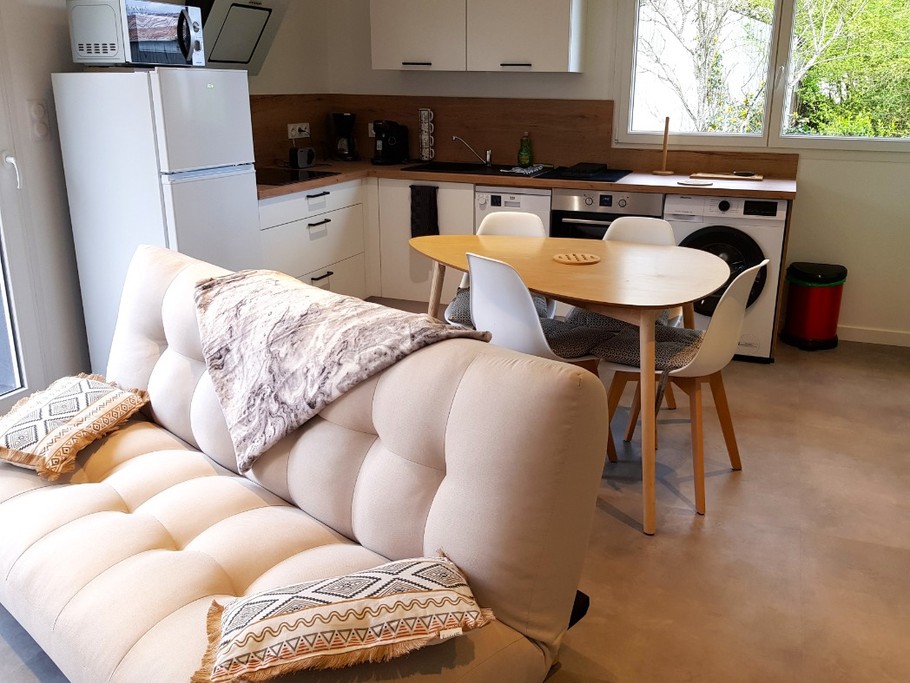 Pièce de vie au rez-de-chaussée avec coin salon avec TV, et coin cuisine et sa table à manger. Canapé convertible pour 2 personnes. Terrasse en bois accessible par un portillon ou par la baie vitrée.