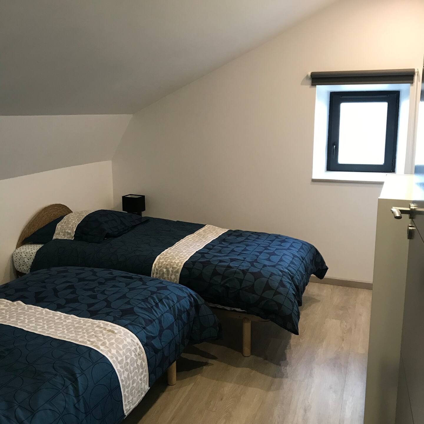Chambre lumineuse avec deux lits simples, idéale pour enfants ou amis.