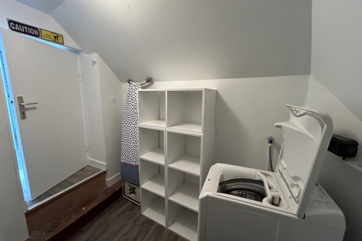 Entrée de l'appartement. A gauche, un escalier menant aux chambres, aux sanitaires et à la buanderie. A droite, la pièce de vie avec coin salon (canapé convertible pour 2 personnes), coin séjour et coin cuisine ouverte.