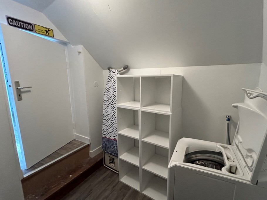 Entrée de l'appartement. A gauche, un escalier menant aux chambres, aux sanitaires et à la buanderie. A droite, la pièce de vie avec coin salon (canapé convertible pour 2 personnes), coin séjour et coin cuisine ouverte.