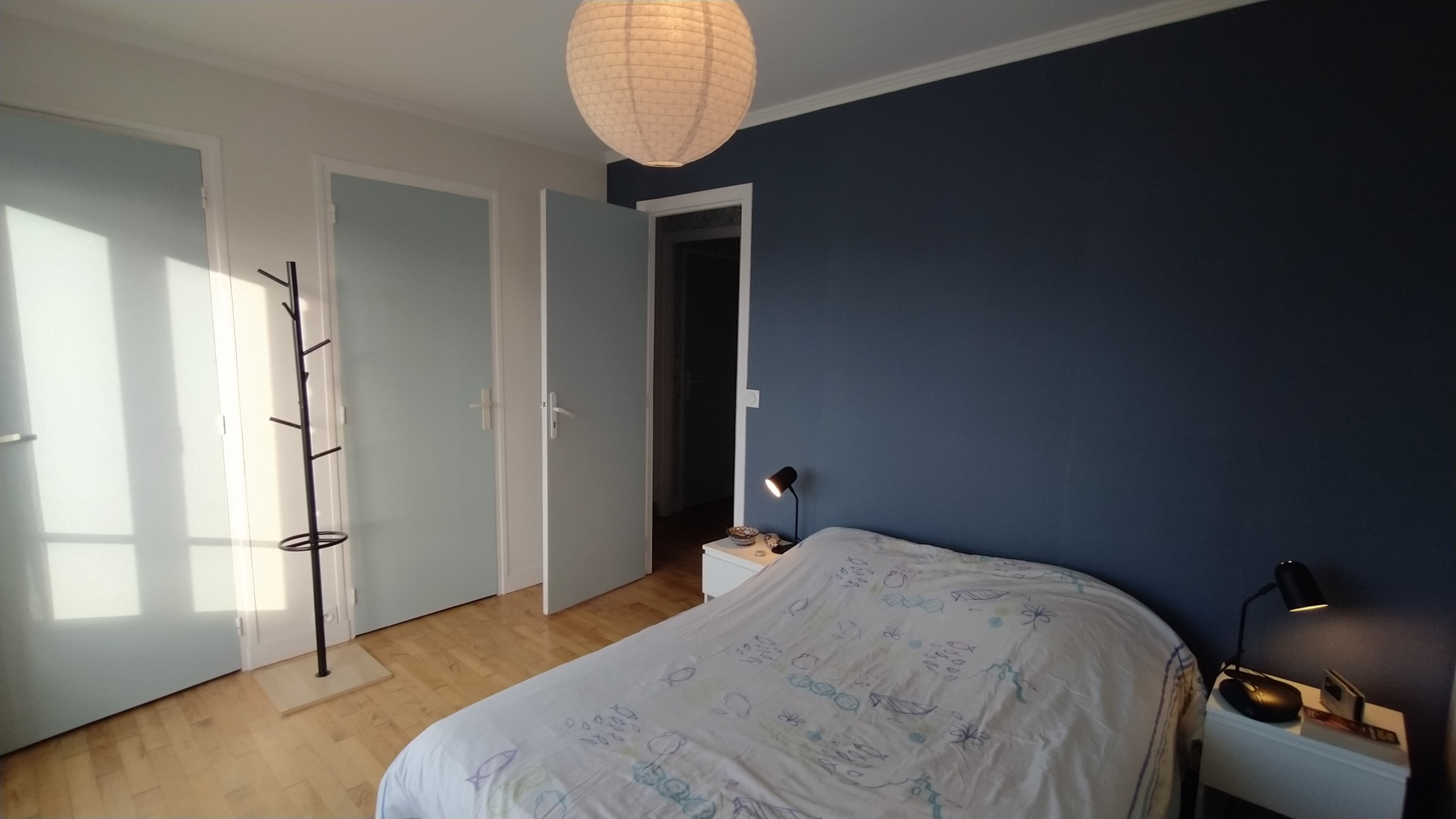 Chambre 1 avec un lit 140 cm, rangements, porte-manteau, et salle d'eau communicante (douche grande dimension et meuble vasque avec miroir)