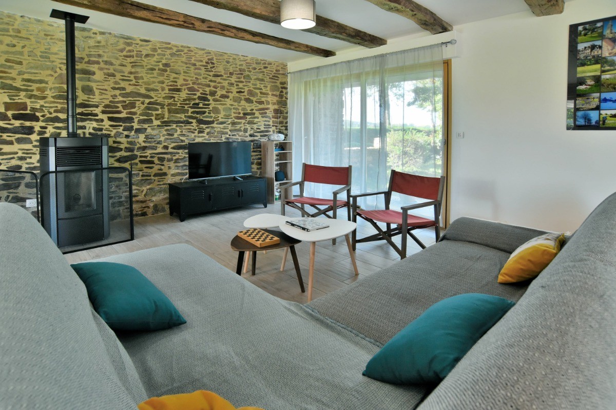 Grande pièce de vie avec poutres apparentes. Coin salon. Poêle à granulés en automne/hiver.