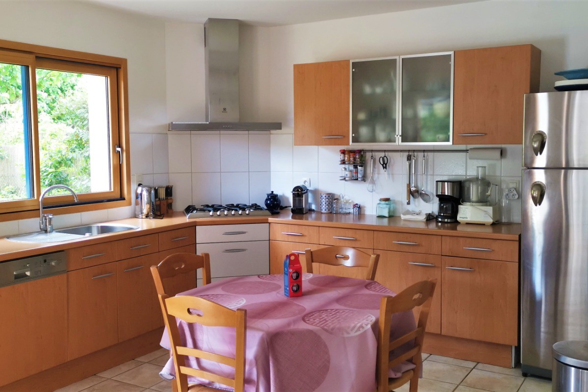 Cuisine toute équipée, avec vue sur le jardin arboré.
