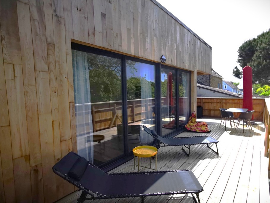 Grande terrasse de plus de 40 mètres carrés avec transats et salon de jardin.