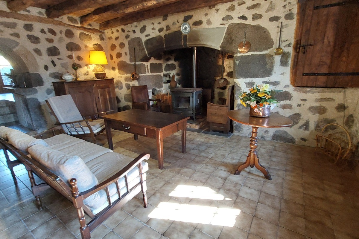 Salon chaleureux avec poêle à bois, canapé et fauteuils confortables dans un gîte de charme."
