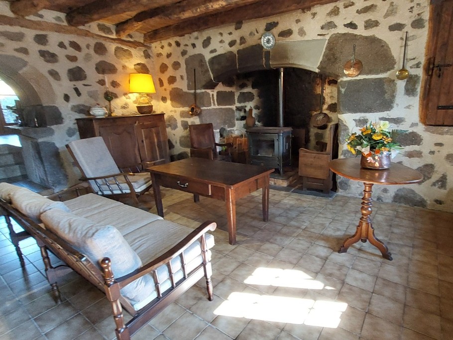 Salon chaleureux avec poêle à bois, canapé et fauteuils confortables dans un gîte de charme."