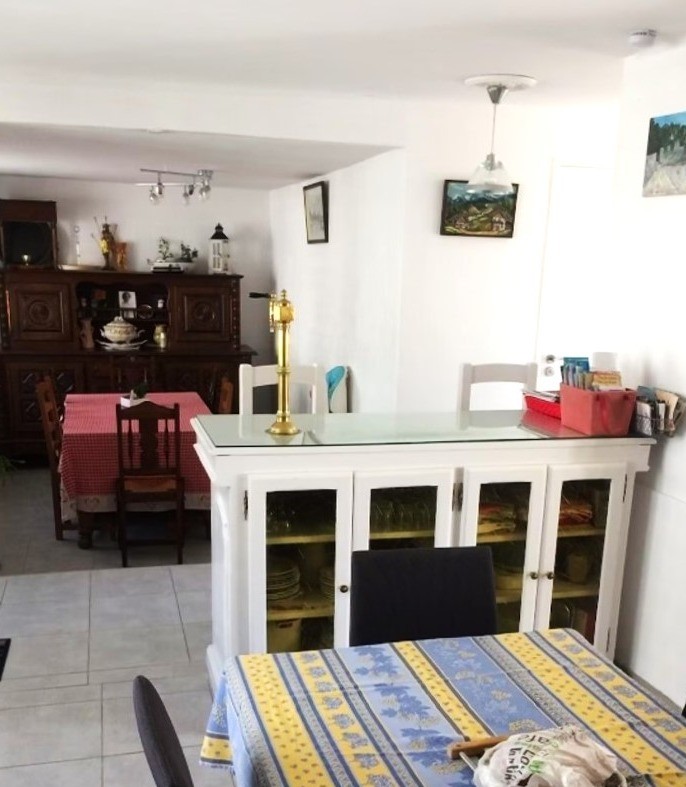 Table de la cuisine en premier plan et table du séjour en 2nd plan. A droite, le salon ouvert avec le poêle à bois