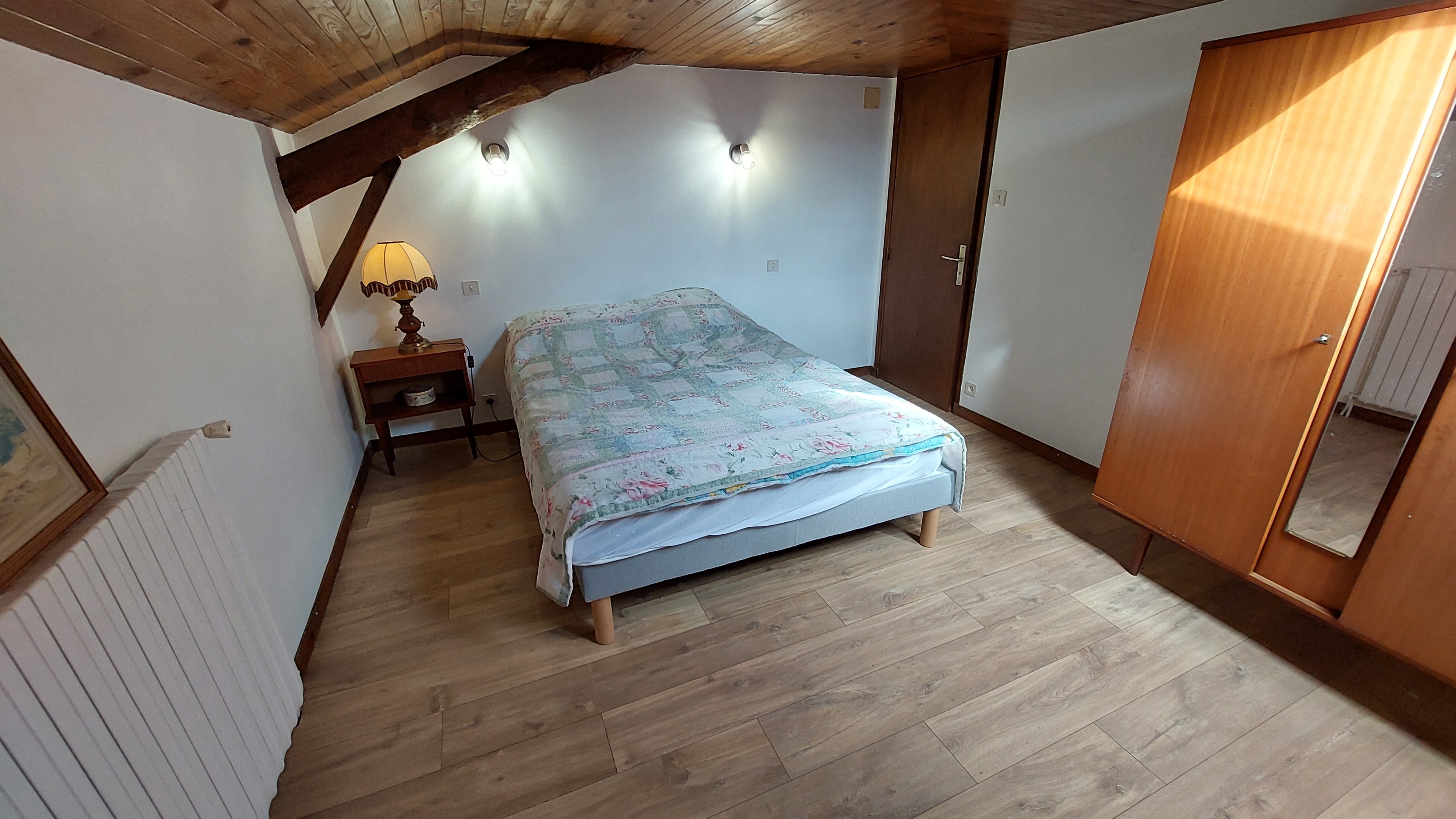 Bedroom with double bed and exposed beams in a gîte in Maurs, Cantal